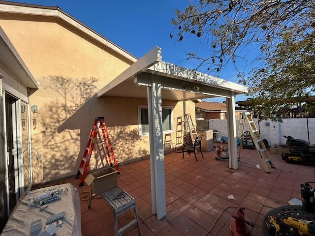 New patio cover installation over a tiled backyard patio