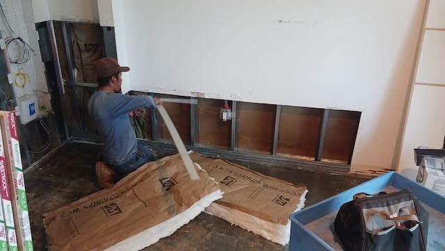 Technician repairing interior wall framing and drywall after termite damage